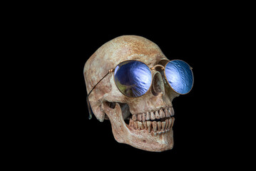 Human skull wears sunglasses on black background