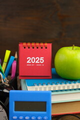 Calendar and new year concept. stack of Multiple books and red mini calendar of 2025 with green...