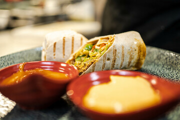 This photo highlights the delicious presentation of a burrito with sauces, making it ideal for food blogs, Mexican recipes, or promoting flavorful and visually appealing dishes.
