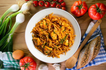 Spanish paella with fideuá and vegetables and chicken. Top view table with decoration.