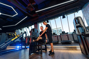 Personal training session in a modern gym. A trainer assists a client with leg exercises in a contemporary gym with large windows, showcasing a bright and inviting atmosphere.