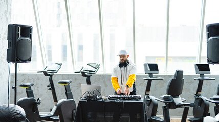 DJ performing live in a modern gym setting. A DJ sets up for a live performance in a contemporary gym, surrounded by exercise bikes and large windows, creating an energetic atmosphere.