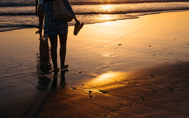 People walking barefoot on the beach at sunset © Raquel
