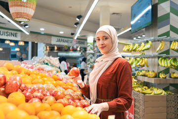Happy mature Asian woman looking  products at grocery store. Costumer buying food at the market. Woman enjoying her time shopping at the grocery store