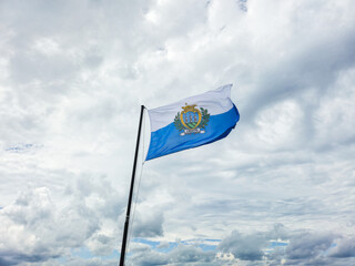 Flag of San Marino with clouds in background.