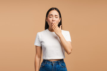 Young asian woman yawning and covering her mouth with hand