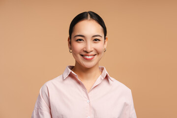 Young asian woman smiling wearing pink shirt on beige background