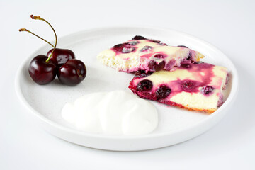 a plate with a piece of baked pudding cake and cherries on it