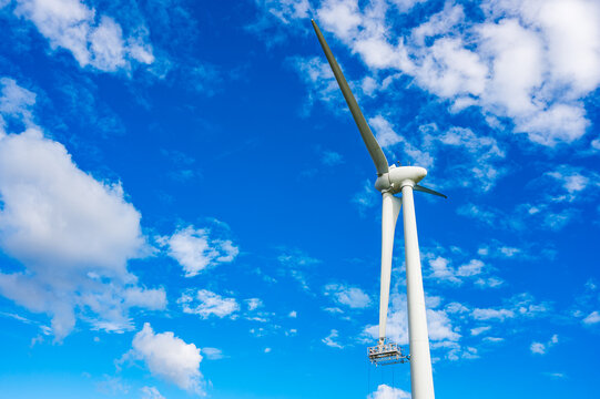 Maintenance service on a wind turbine in Sweden under a clear blue sky with clouds