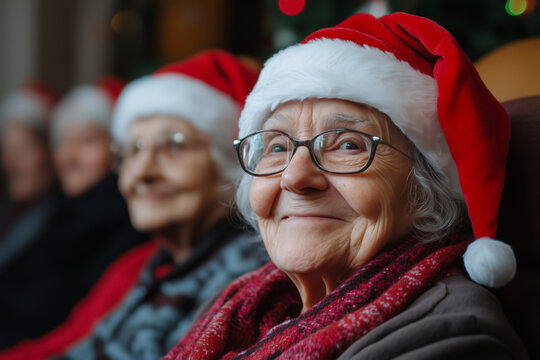 A senior woman portrait, wearing a Santa hat while enjoying a Christmas holiday gathering with her friends. An old woman smiling at the camera, celebrating the Christmas eve.