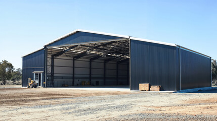 Large steel farm shed standing open on farmland