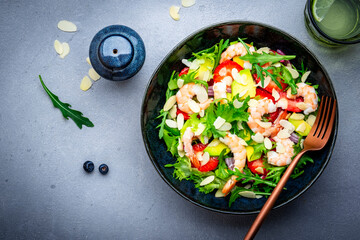 Shrimp salad with strawberries, onions, lettuce and almonds, gray background, top view