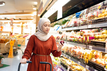 Happy mature Asian woman looking  products at grocery store. Costumer buying food at the market. Woman enjoying her time shopping at the grocery store