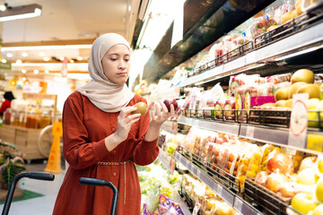 Happy mature Asian woman looking  products at grocery store. Costumer buying food at the market. Woman enjoying her time shopping at the grocery store