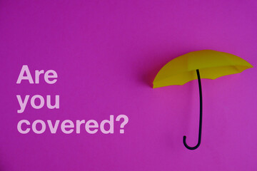 text  ARE YOU COVERED on a  isolated on a purple background. insurance concept
