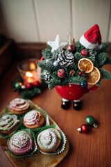 Christmas cupcakes and beautiful Christmas bouquet in a bowl on the table by the window. 