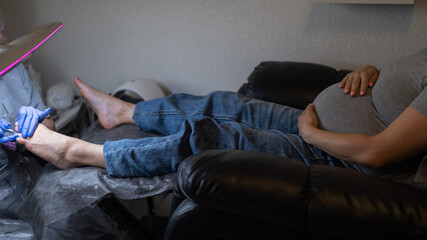 Pregnant woman on a hardware pedicure procedure in a beauty salon. 