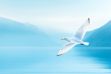 A seagull gracefully soars over tranquil waters surrounded by misty mountains at dawn