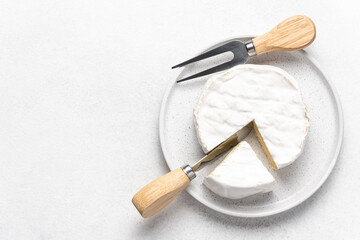 Soft camembert cheese on plate on white background top view with copy space