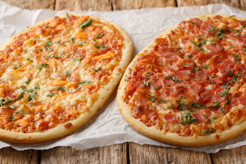 Homemade Pinsa Romana with Three cheeses, ham and tomato sauce close-up on parchment on wooden table. Horizontal