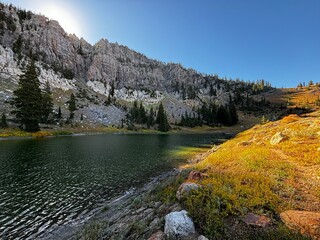 Sunrise on High Creek Lake with grey rock cliffs and pine trees reflecting in the alpine clear...