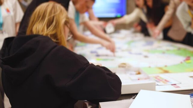 Process of playing tabletop board game on the table, fun with friends and family in room indoors, board game concept, company group of students adults play board games, roll the dice on a game map