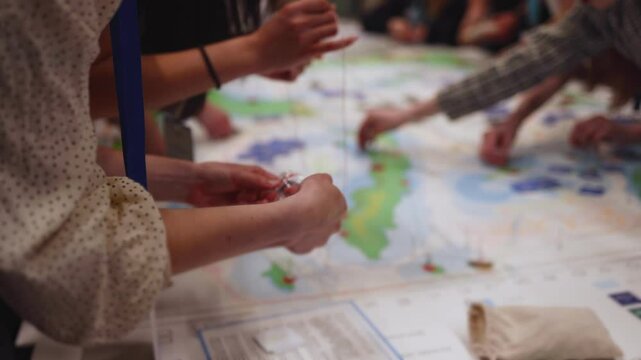 Process of playing tabletop board game on the table, fun with friends and family in room indoors, board game concept, company group of students adults play board games, roll the dice on a game map
