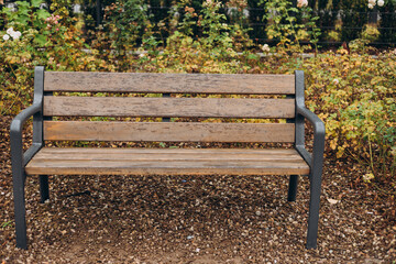 A modern wooden bench with trash bin standing in the park. Comfortable bench in recreation area. City improvement, urban planning, public spaces.