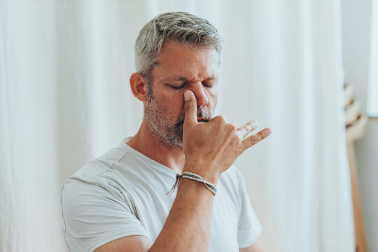 A man sitting in lotus position, practicing alternate nostril breathing exercises during a meditation session