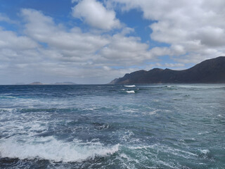 Landscape with the Atlantic Ocean in the mist from Famara beach and Graciosa Island in the background