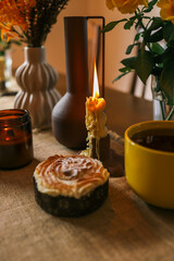 Cozy dining table with a warm autumnal atmosphere featuring a yellow cup, an open book, a muffin, and decorative vases with yellow flowers. The scene evokes a sense of relaxation and comfort