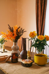 Cozy dining table with a warm autumnal atmosphere featuring a yellow cup, an open book, a muffin,...