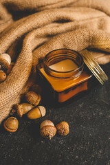 Jar candle and acorns on a knitted fabric background, creating a cozy autumn atmosphere