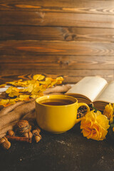 Cozy autumn scene with tea, pastry, yellow roses, and warm knitted sweaters