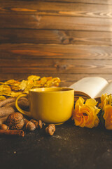 Cozy autumn scene with tea, pastry, yellow roses, and warm knitted sweaters