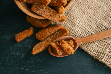Wooden bowl filled with crispy rye croutons placed on a burlap cloth, creating a rustic snack...