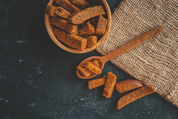 Wooden bowl filled with crispy rye croutons placed on a burlap cloth, creating a rustic snack...