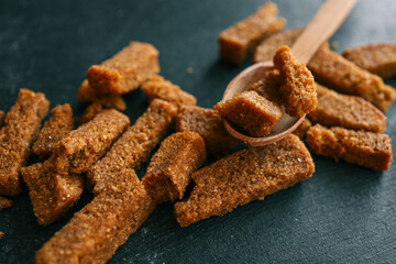 Wooden bowl filled with crispy rye croutons placed on a burlap cloth, creating a rustic snack presentation