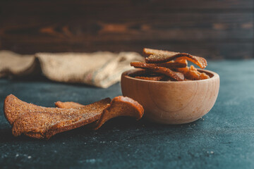 Wooden bowl filled with crispy rye croutons placed on a burlap cloth, creating a rustic snack presentation