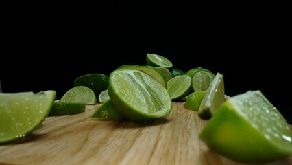 Close-up, a vibrant slice of fresh lime rests upon a rustic wooden cutting board, exuding freshness and vitality. The translucent membranes of the green lime slice placed on cutting board. Comestible.