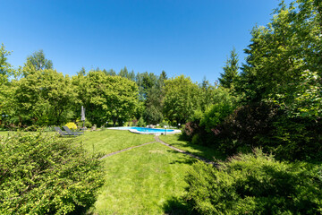 A private area with a swimming pool and sun beds, closed from prying eyes by dense green .shrubs,...