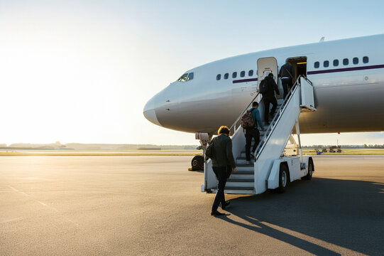 Passengers boarding the aircraft from the stairs of a passenger aircraft at the airport.
