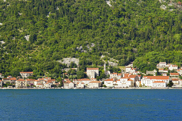 View of Perast from the water: the old town built against the mountain in Mediterranean style and the waters of the Adriatic Sea. Landscape from the tourist place of Kotor Bay, Montenegro.