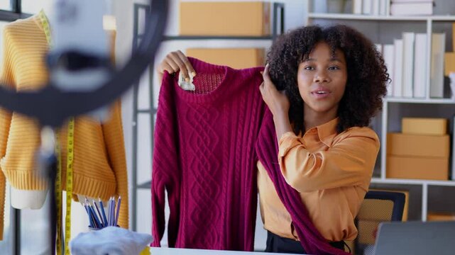 Fashion designer showcasing a new sweater during a livestream from her workshop, highlighting the latest collection