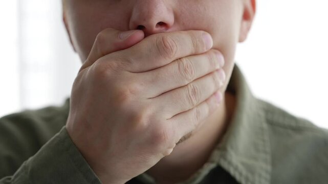 A man closes his mouth so as not to make sounds.
The man is trying not to talk.
Closed mouth.
Gesture of silence.
Complete silence.
Shut your mouth.
Don't say anything