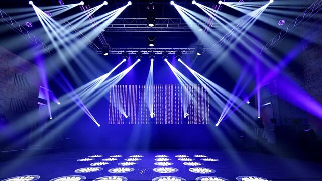 Bright white spotlights illuminate a dark stage with a blue backdrop