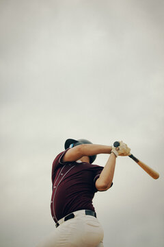 Baseball player in action swinging a bat on a cloudy day