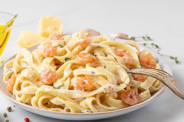 Alfredo fettuccine pasta with shrimps, creamy sauce, fresh thyme, parmesan cheese, garlic, olive oil in a plate with fork. Italian food