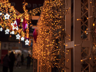 Christmas and New Year holidays decorations of streets with trees and shops with multicolored christmas string fairy lights glowing in the darkness outdoors. Winter holidays celebration concept.