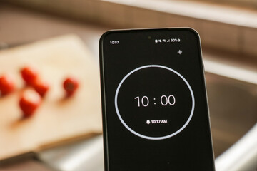 A phone with a black and white 10-minute timer for recipe cooking in kitchen with fresh food...